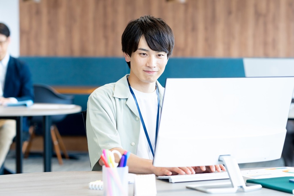パソコンに向かって笑顔を見せる男性会社員