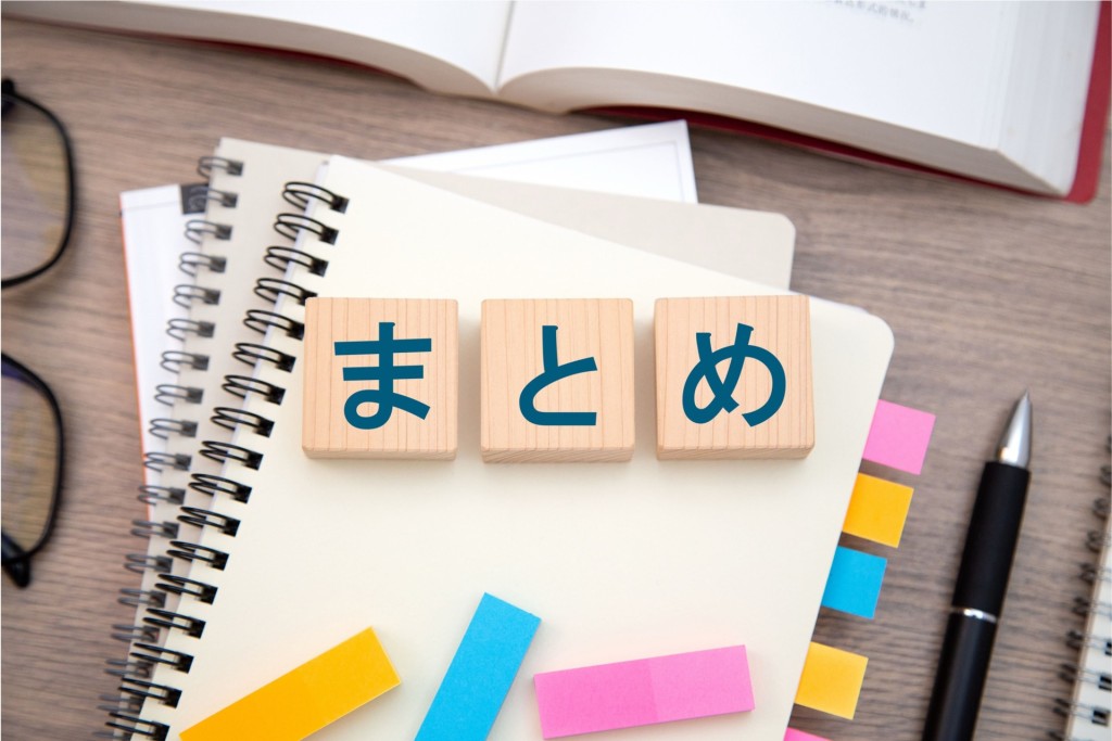 ノートや文房具の上に置かれた「まとめ」と書かれた木製ブロック