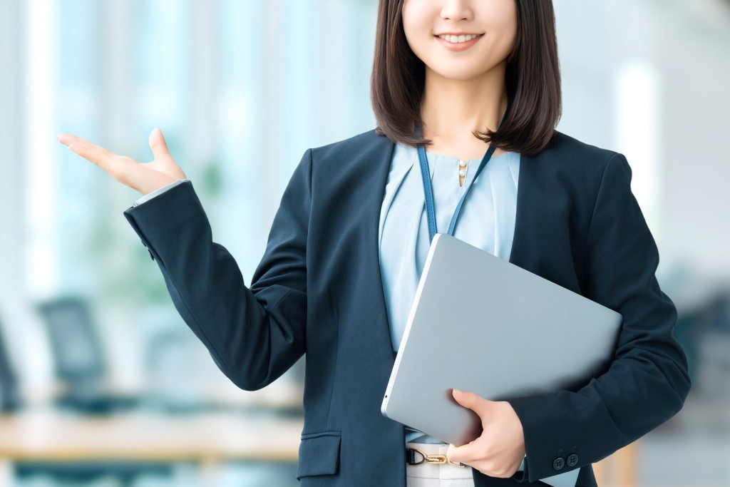 ノートPCを持ち笑顔で案内する女性