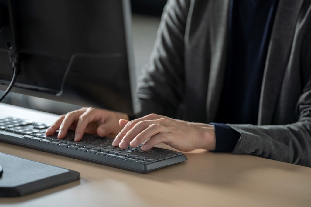 パソコンのキーボードをタイピングする男性の手元