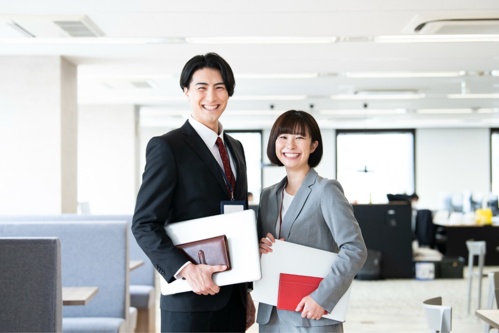 オフィスで笑顔を見せるスーツ姿の男女