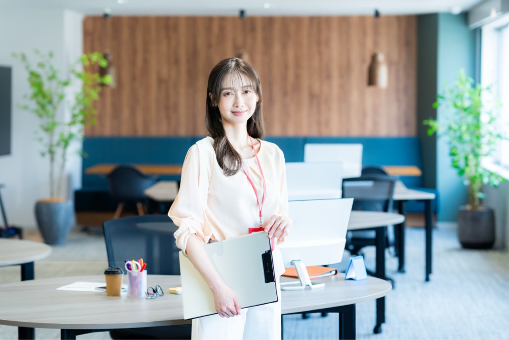 オフィスでバインダーを持ち微笑む女性社員