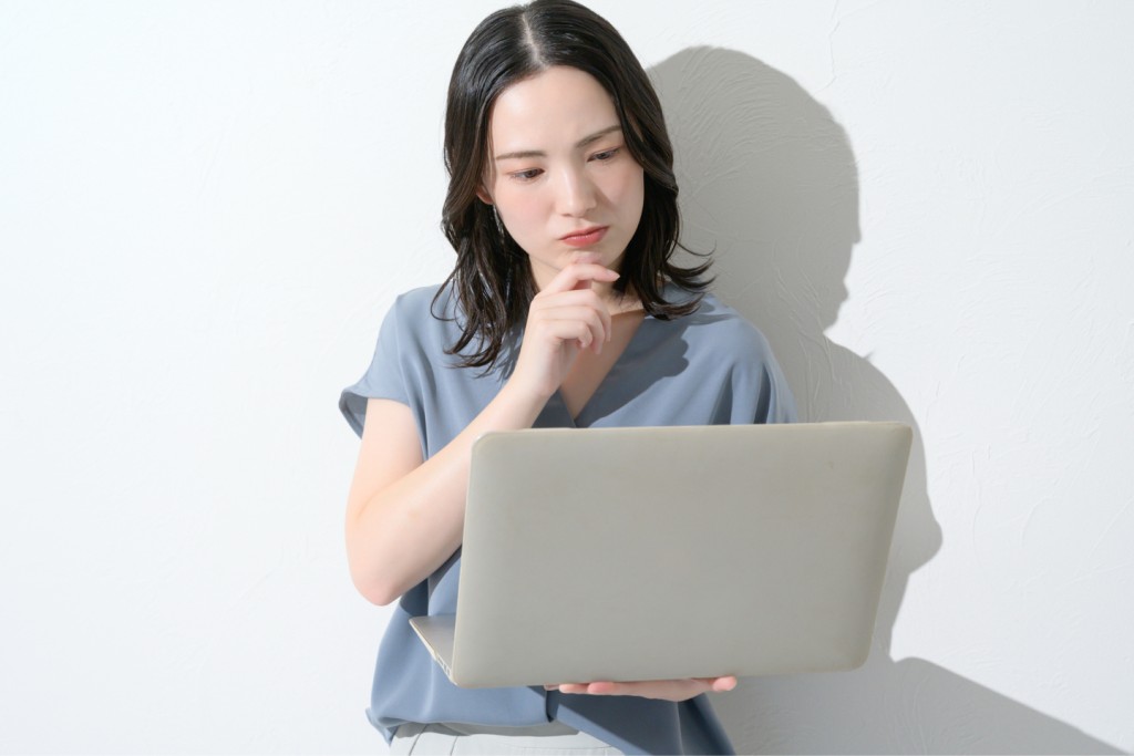 ノートパソコンを持ち悩む表情を浮かべる女性