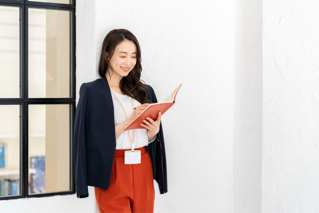 手帳にメモを記入する女性ビジネスパーソン
