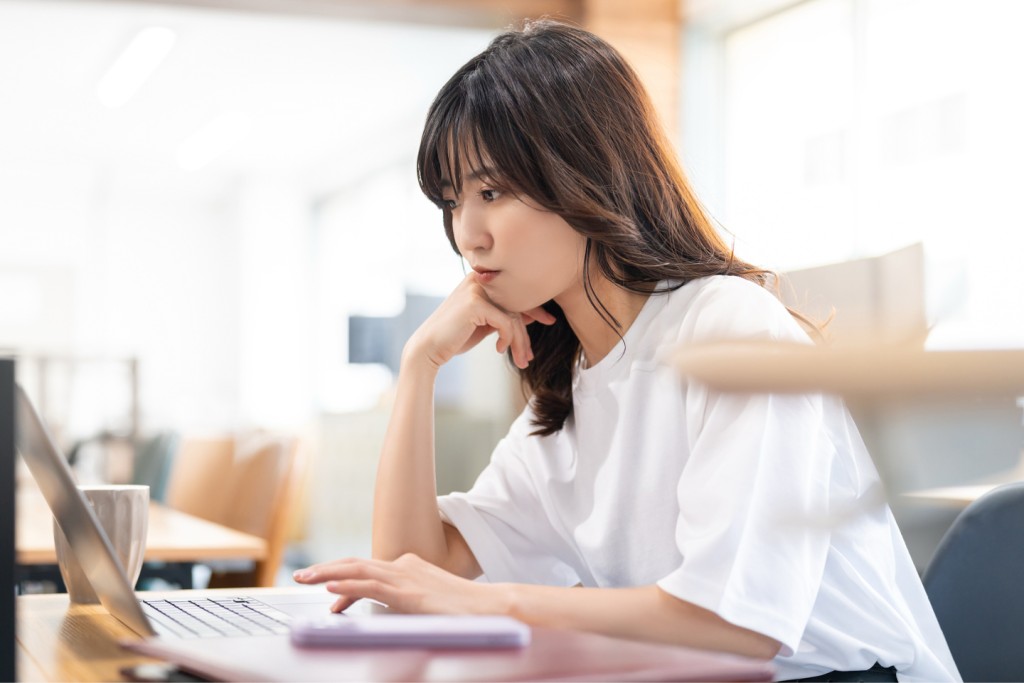 ノートパソコンの前で真剣に悩む女性