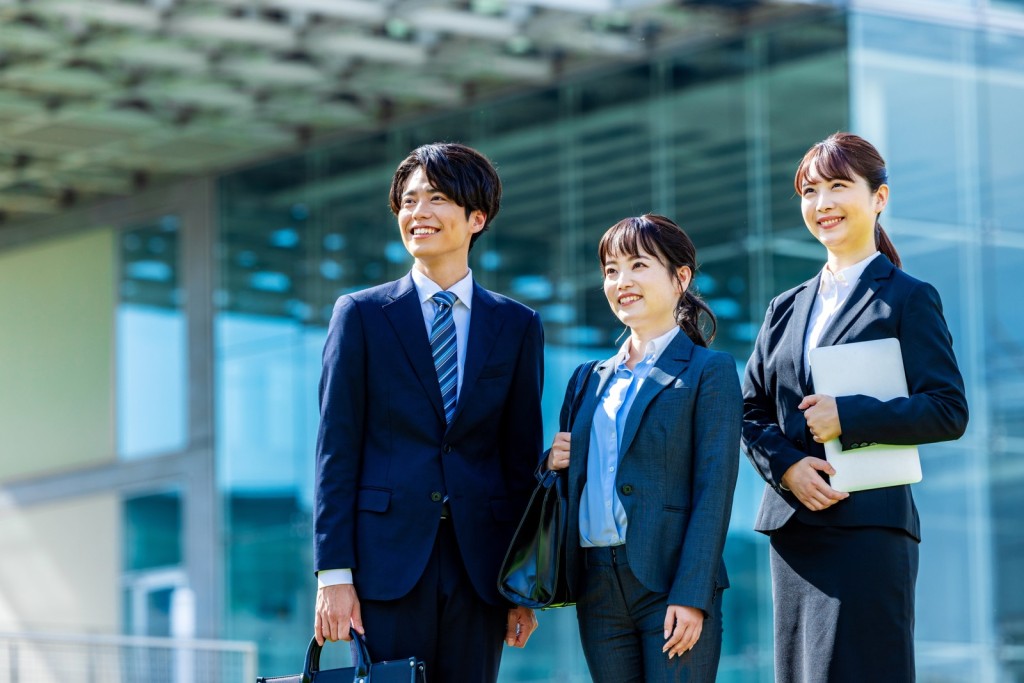 笑顔で並び立つスーツ姿のビジネスパーソンの男女3人